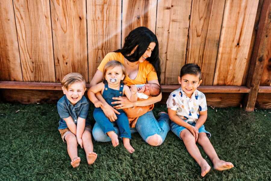 Mom takes a photo with her four sons under five in their backyard