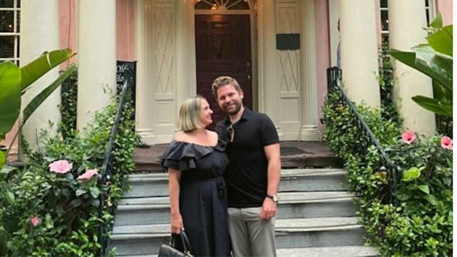 Couple in black outfits standing outside house