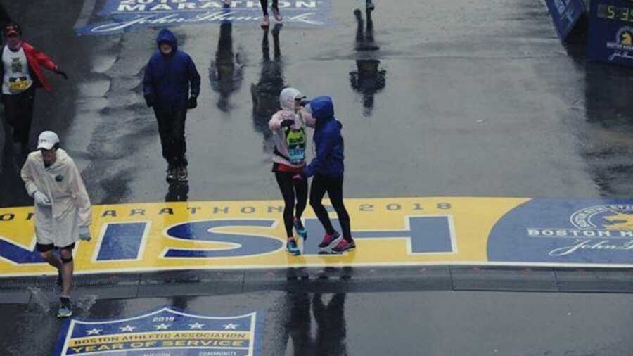 Two people in rain slickers hugging at the Boston Marathon finish line