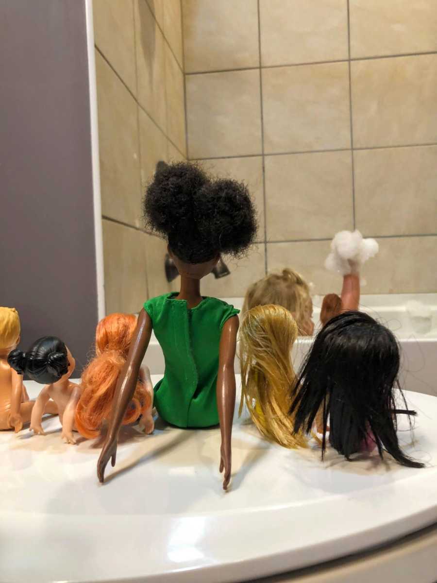 Mom teaching daughter lesson on diversity and kindness snaps photo of daughter playing in tub with Barbies