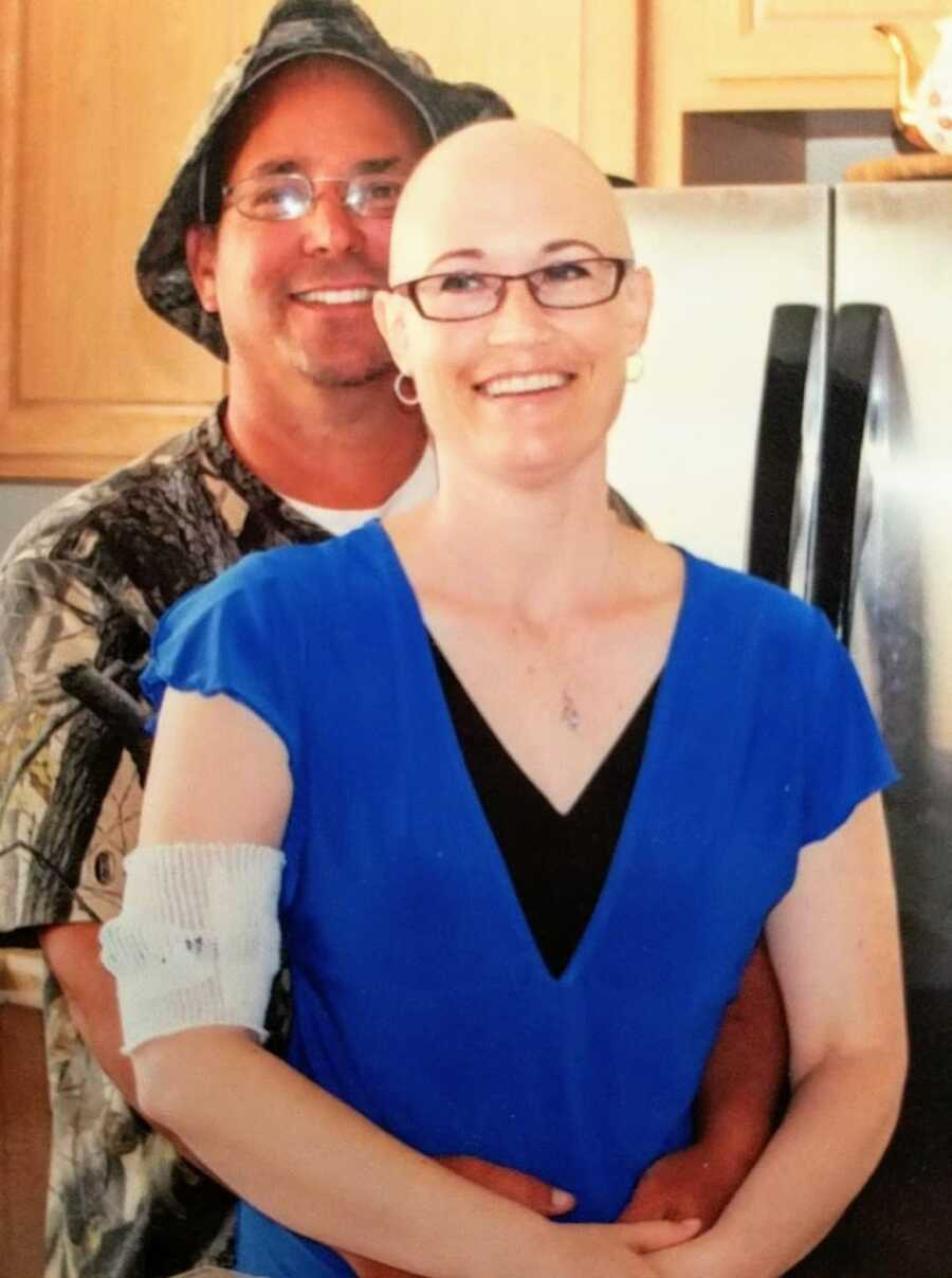Woman battling rare choriocarcinoma cancer stands with her husband as they both smile big