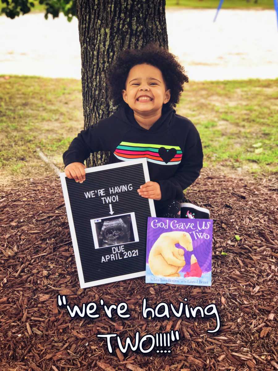 Little girl announces her parents' twin pregnancy with a sign and a book titled 'God Gave Us Two'