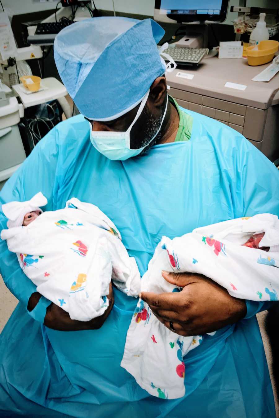 Girl dad holds his twin daughters in the OR, one born still and one with ancencephaly