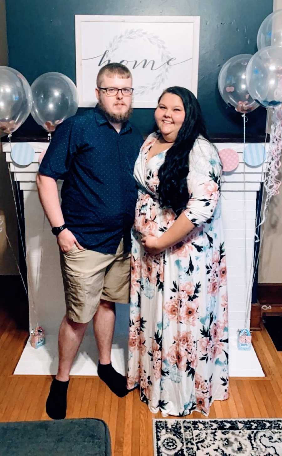 Young couple pregnant with their rainbow baby take a photo together at their baby shower
