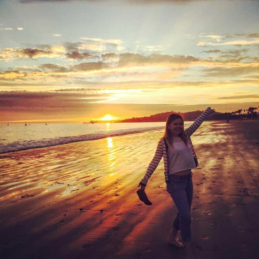 Young college student studying abroad in Europe takes a photo on a European beach during the sunset