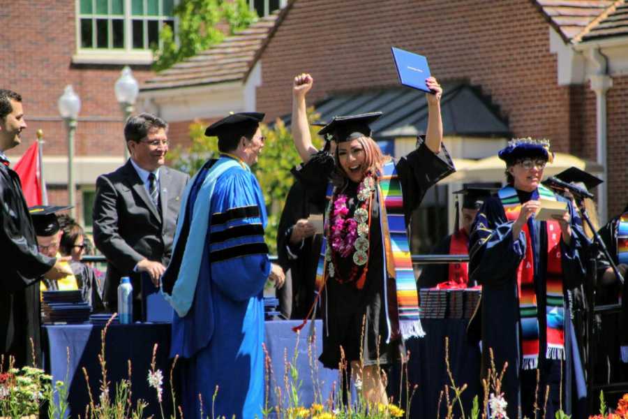 First generation college student celebrates while walking across the stage and receiving her diploma