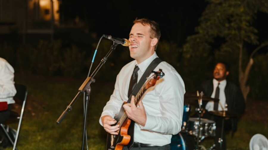 Man singing passionately into microphone and playing guitar