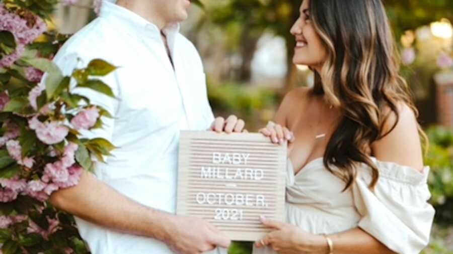 Couple holding up baby announcement and expected due date