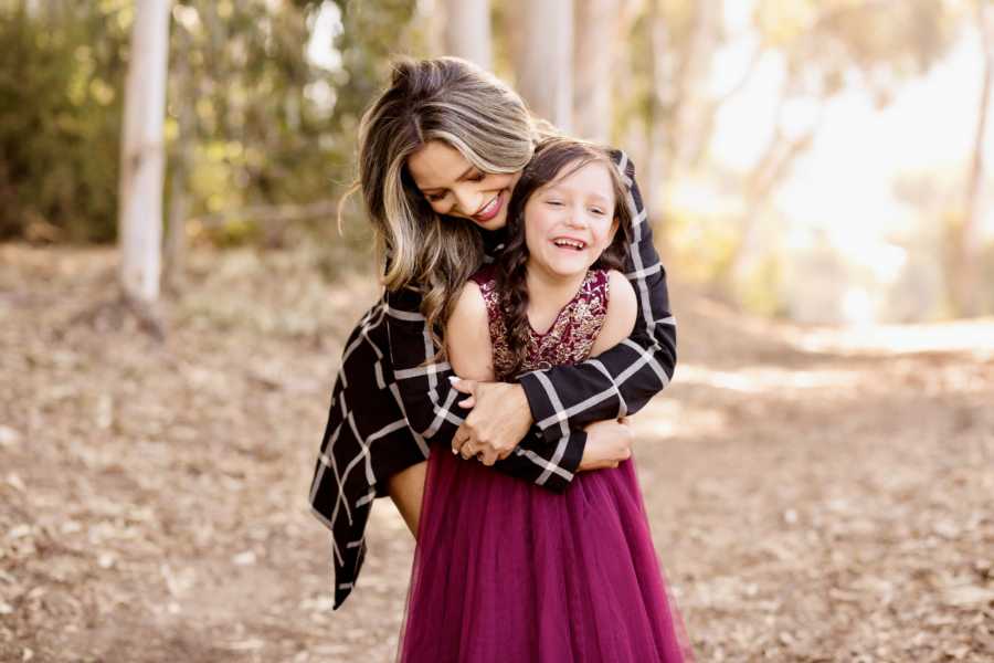 Young widowed mother hugs her only daughter during a fall photoshoot in the woods together