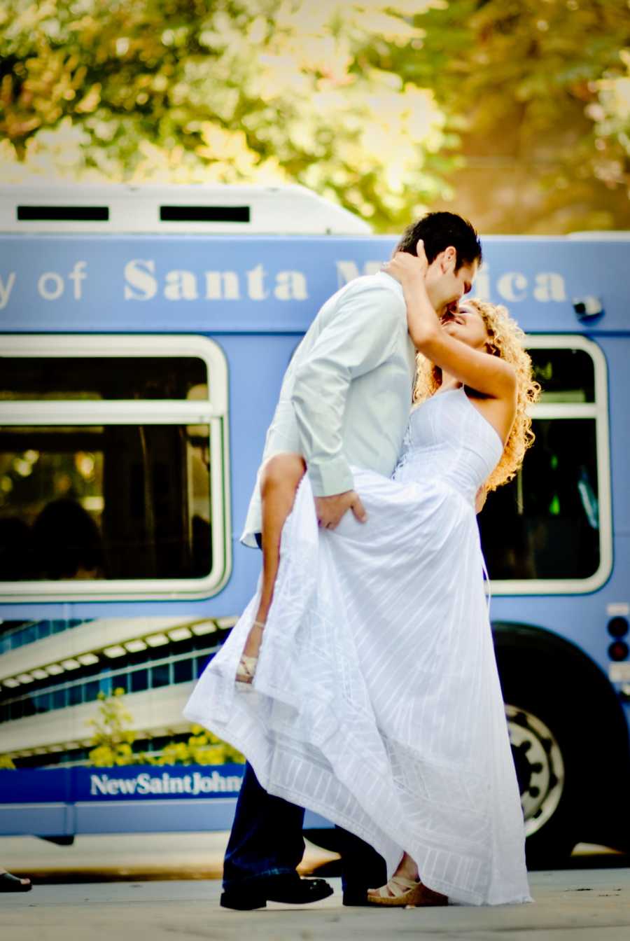 Young couple celebrate their love in intimate kiss during a photoshoot with a Santa Monica bus behind them