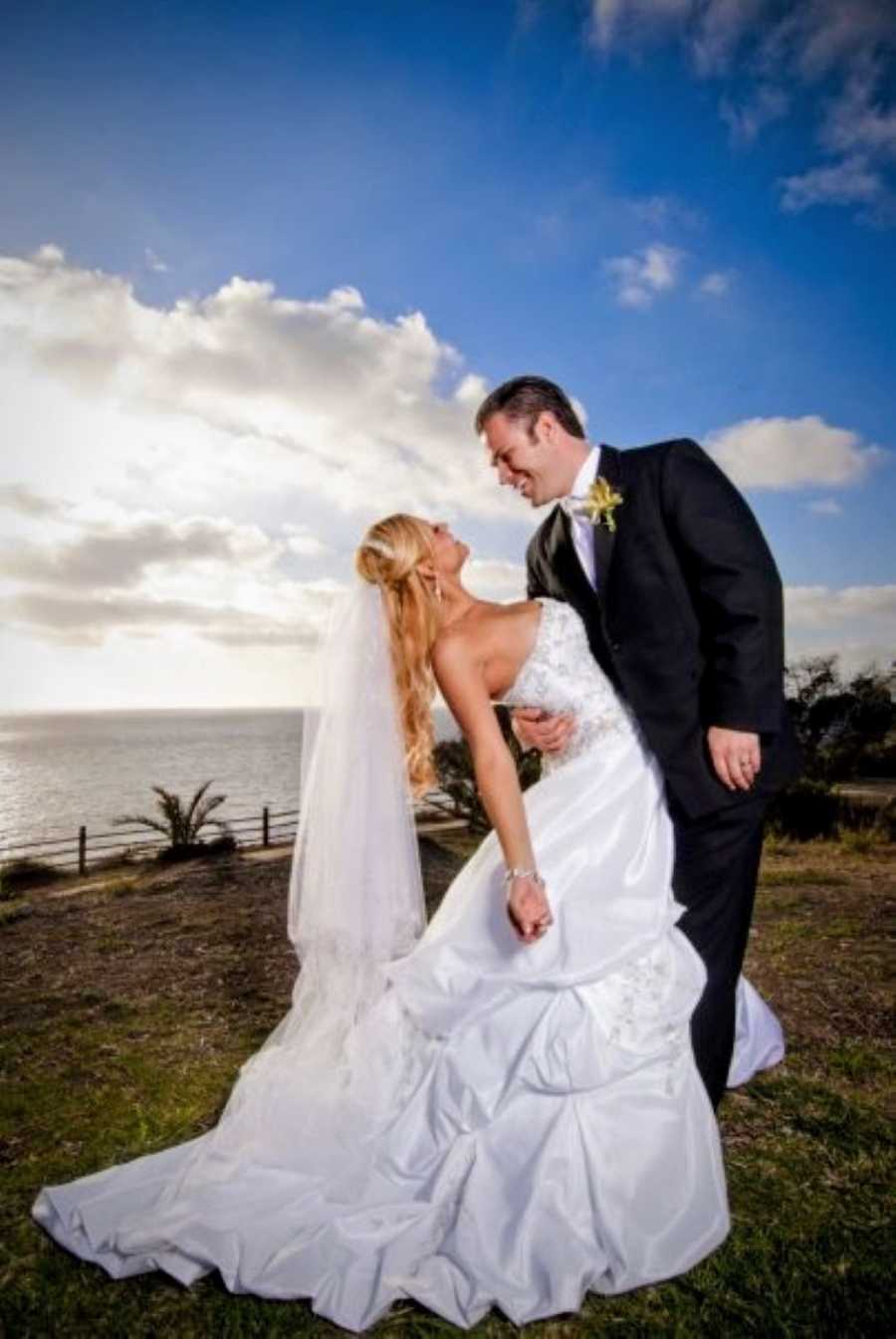 Newlywed couple take beautiful photo together overlooking a cliff at the Point Vicente Lighthouse in California