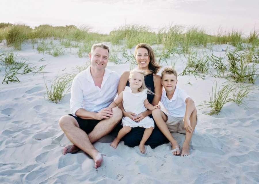 Family of four smile for a photo during a beach photoshoot