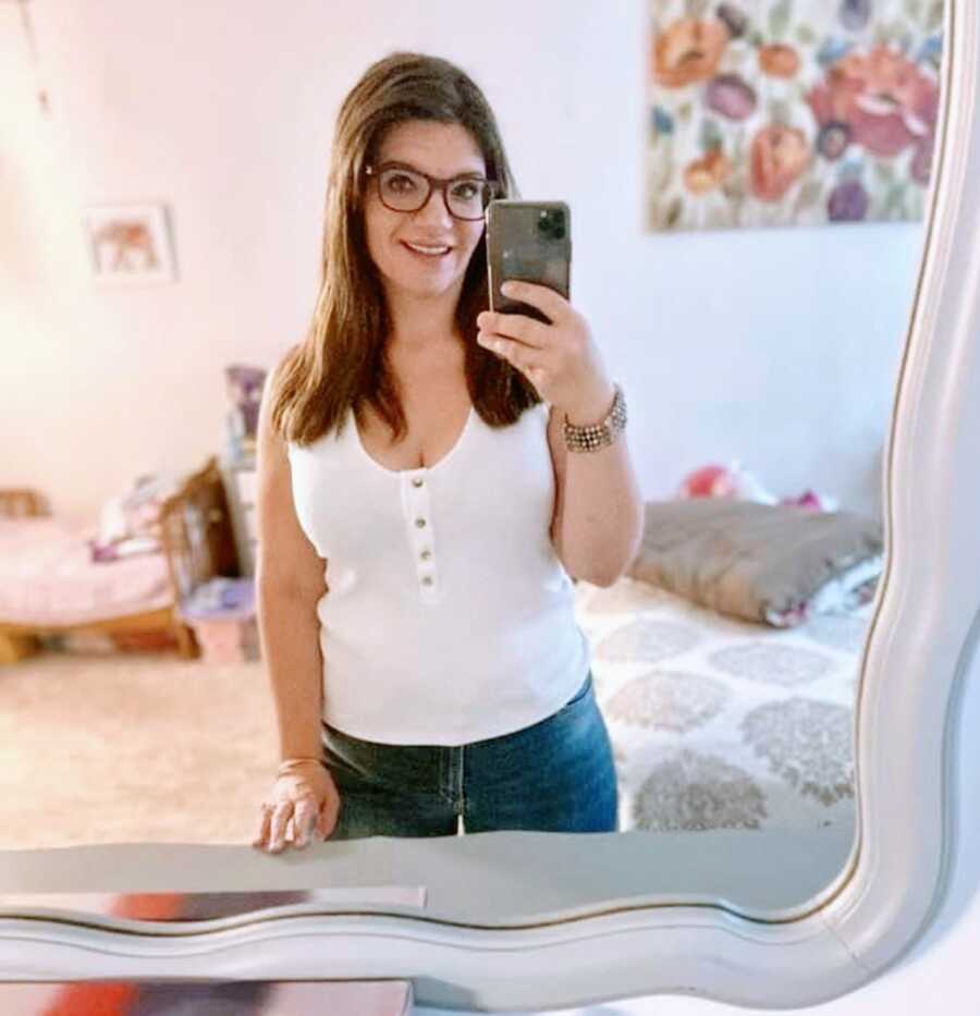 Single mom of three takes mirror selfie in white tank top and jeans