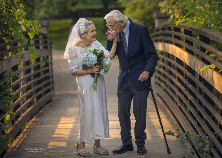 Elderly man walks with a cane and kisses his wife's hand on their 50th anniversary