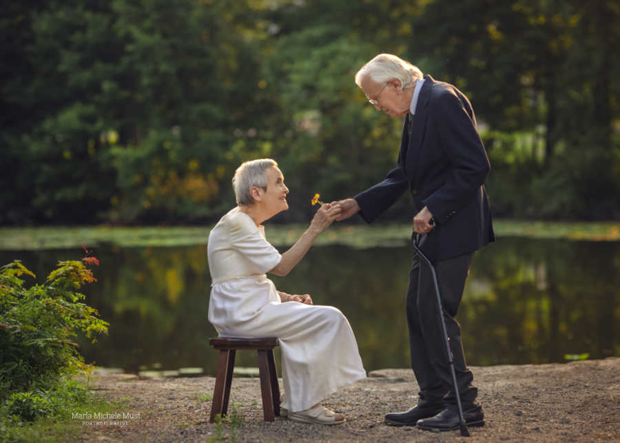 Elderly man gifts his wife of 50 years a flower during their wedding anniversary photoshoot