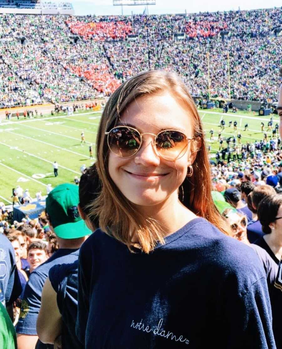 College freshman takes a photo at a football game in the University of Notre Dame football stadium