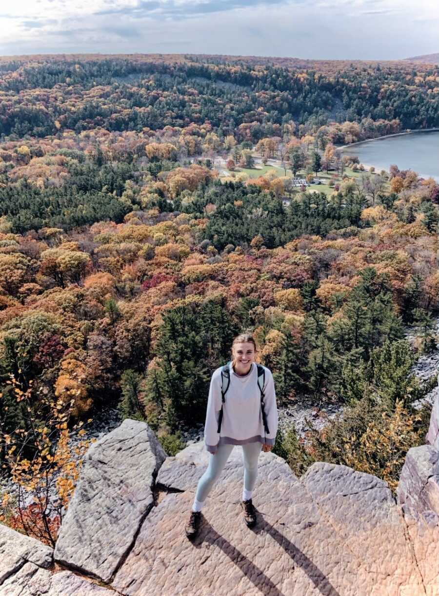 Young high school girls takes a photo with the world at her feet during a hiking trip with her dad