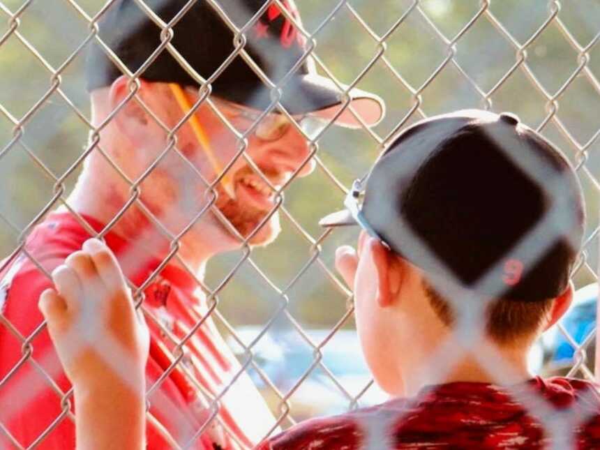 在一场比赛中，父亲和棒球教练对着儿子和他的队友微笑