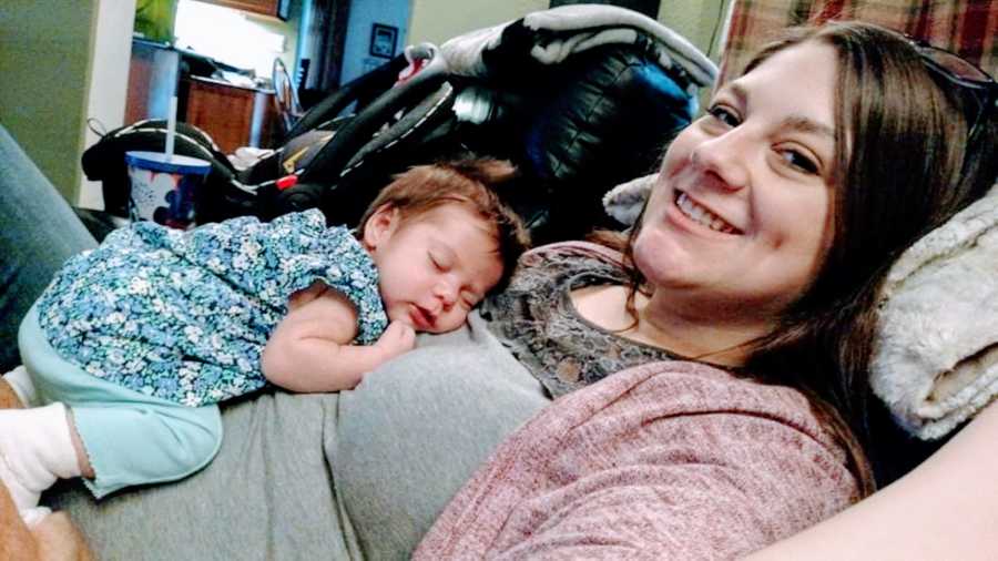 Mom of three takes photo of her newborn daughter curled up on her chest and sleeping in a blue outfit