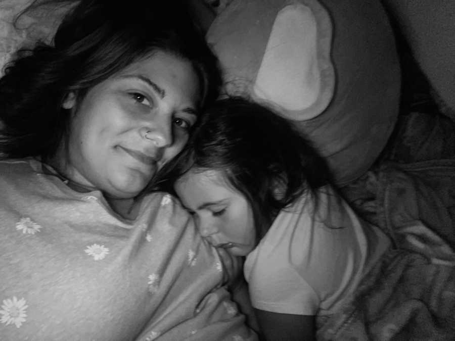 Mom and daughter snuggle together in bed after daughter grows too big to lay on her moms chest