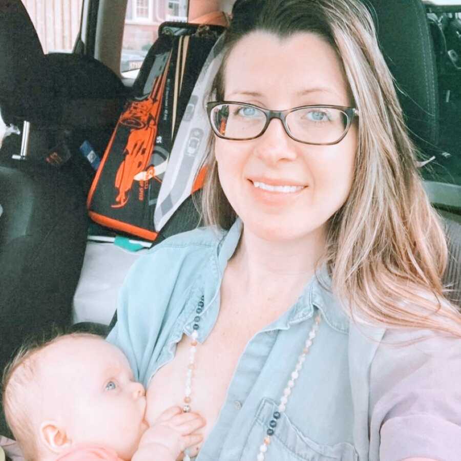 Mom of two breastfeeds her young child while sitting in the car