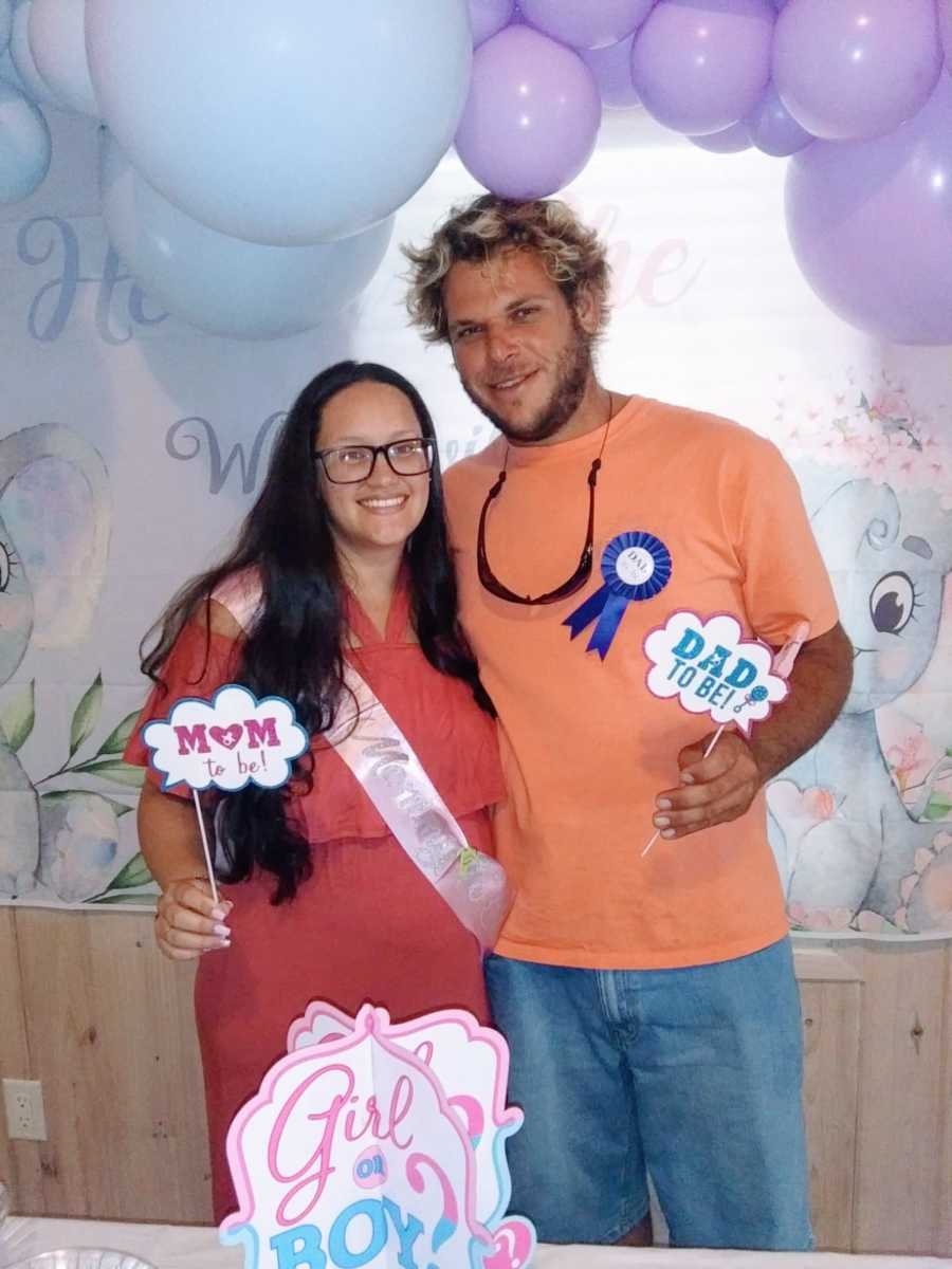 Young couple expecting their first child together take a photo at their gender reveal party