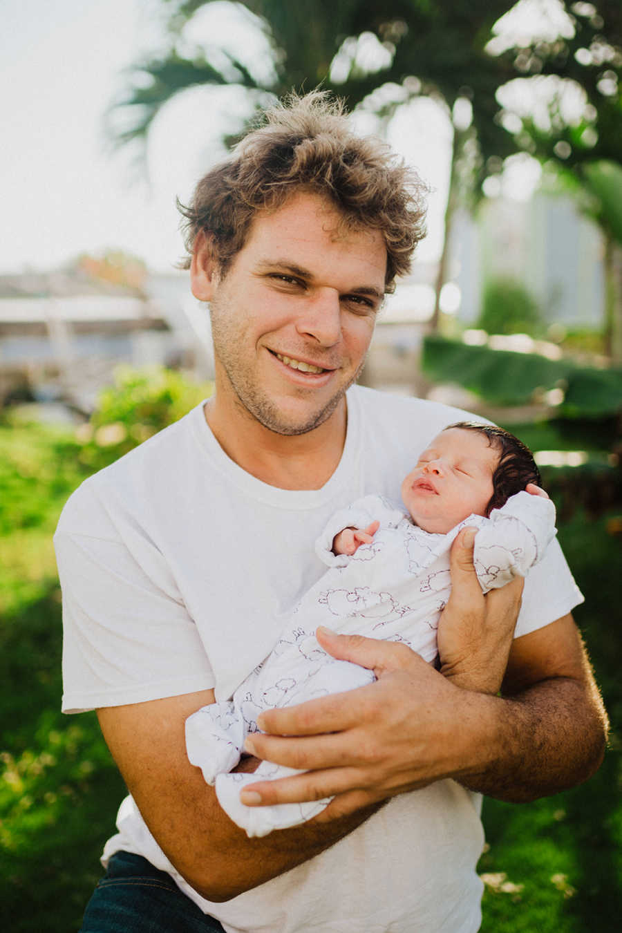 Young dad holds his newborn son with a limb difference