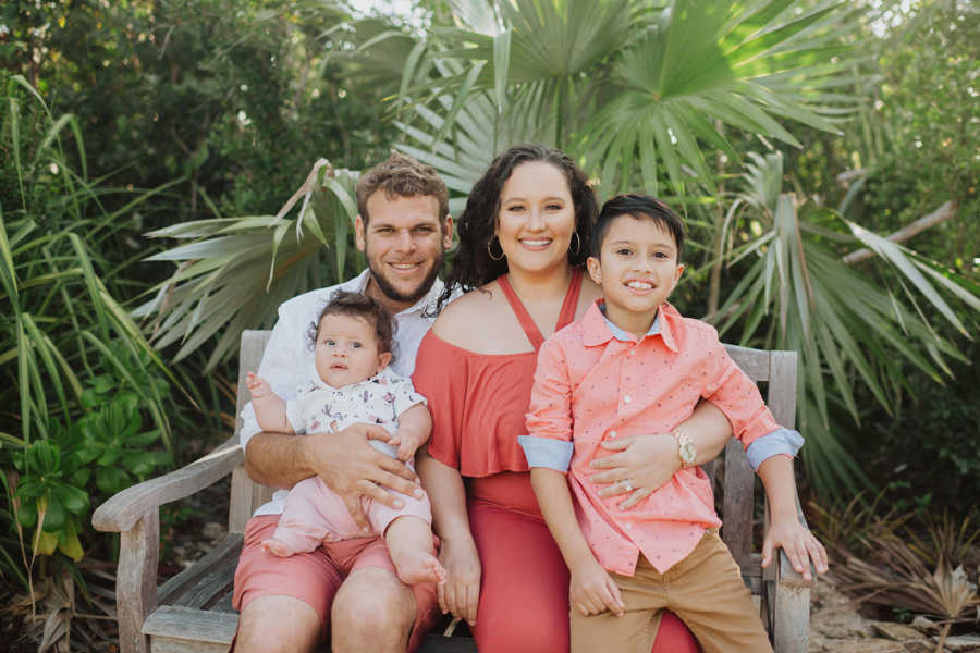 Family of four take family photo together in color-coordinated outfits