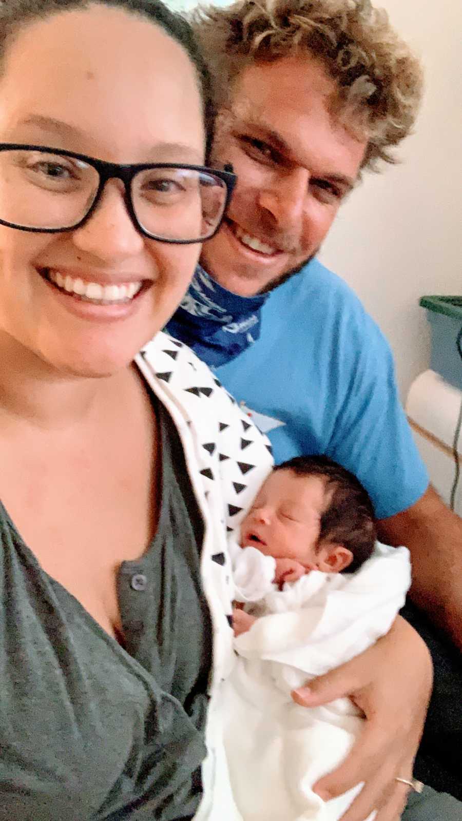 Young couple hold their newborn son born with a limb difference while he's still in the hospital