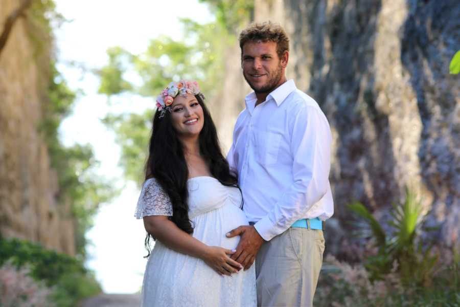 Young couple take pregnancy announcement photos while they both hold the woman's baby bump
