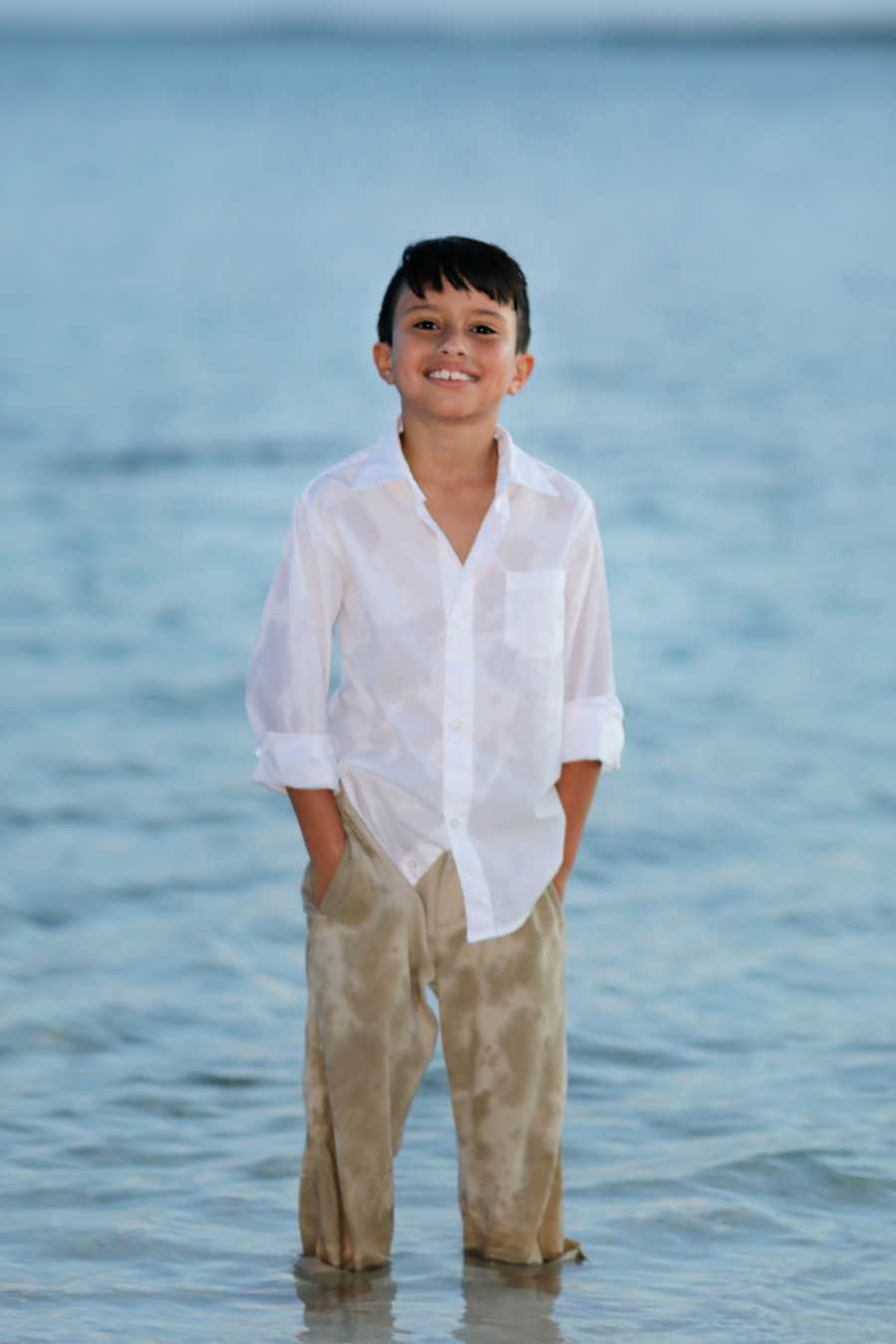 Young boy with epilepsy smiles on the beach during a family photoshoot