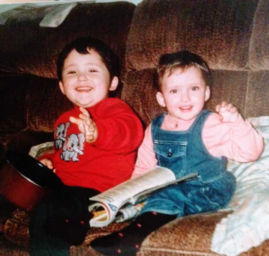 Little sister sits on the coach in denim overalls while sitting next to her brother with asthma