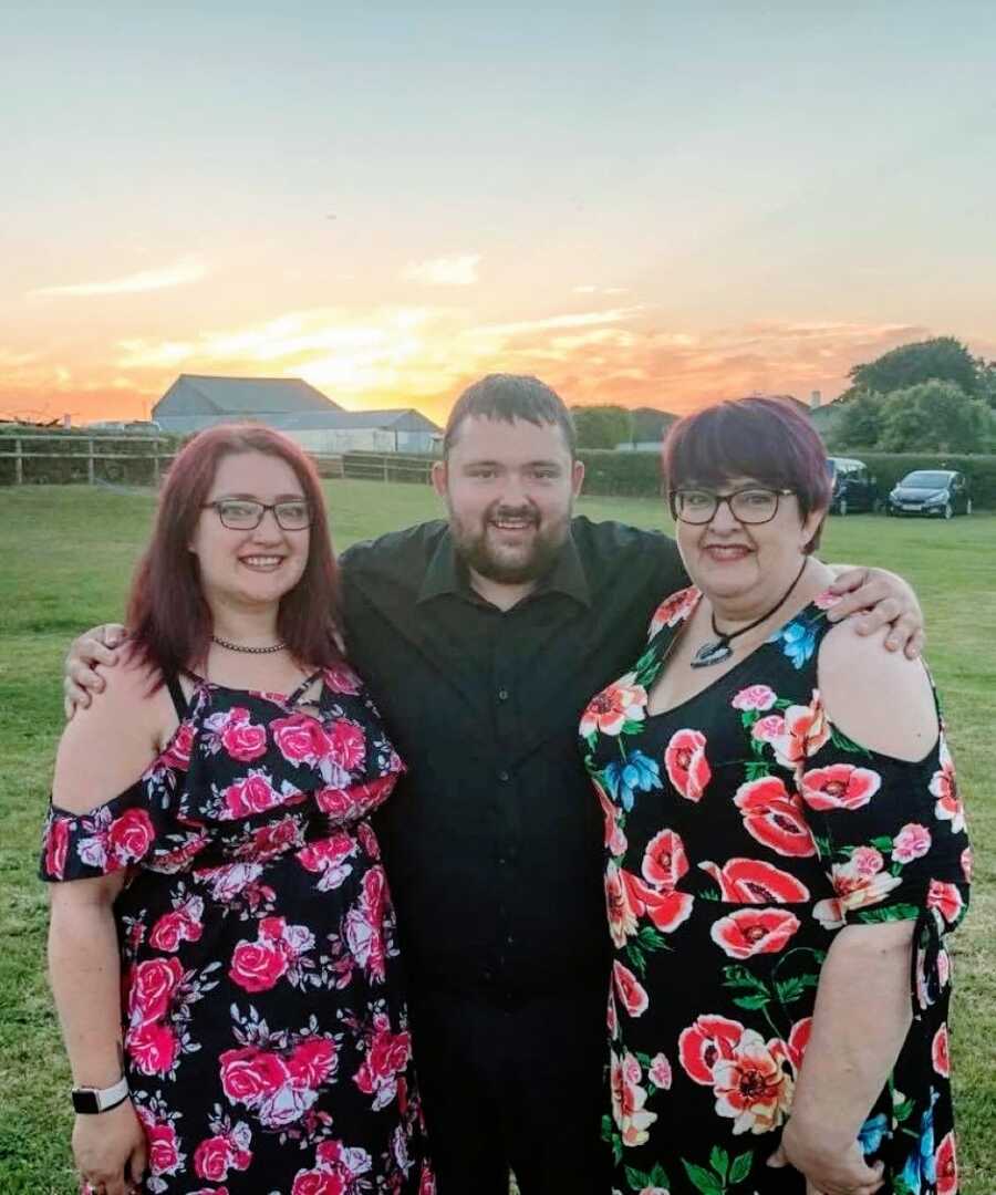 Woman with severe asthma and Crohn's disease takes a photo with her brother and mother with the sunset behind them