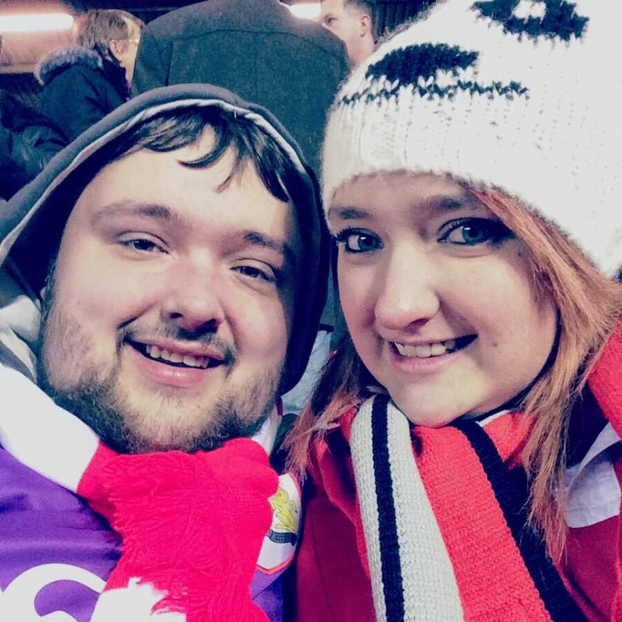 Brother and sister take a selfie together while bundled up in warm clothes as a sporting event