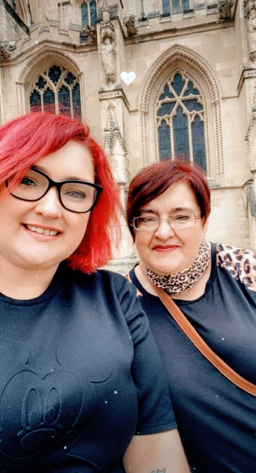 Woman with brittle asthma takes a selfie with her mother while standing in front of a cathedral on vacation
