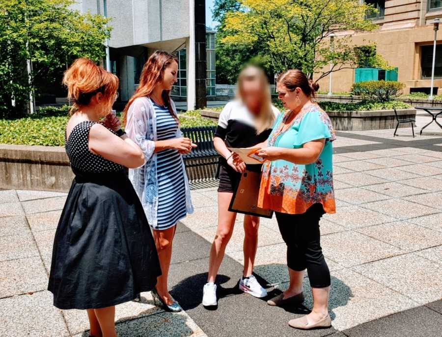 Woman graduating from recovery program looks at her certificate with her probation officer