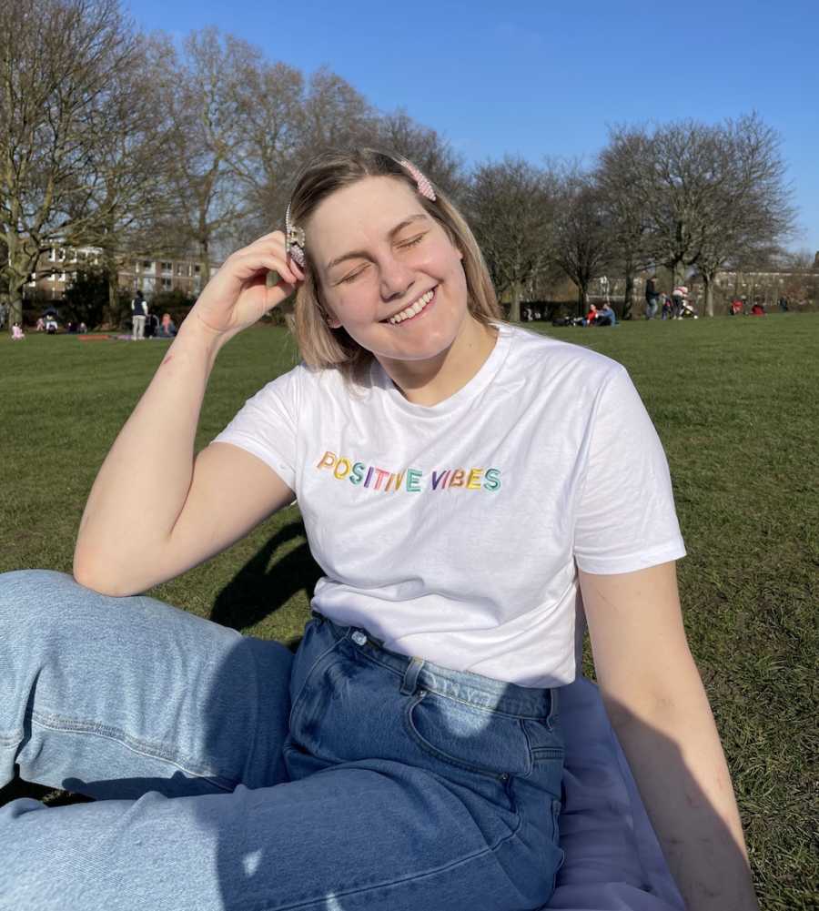 woman smiling wearing a "positive vibes" shirt