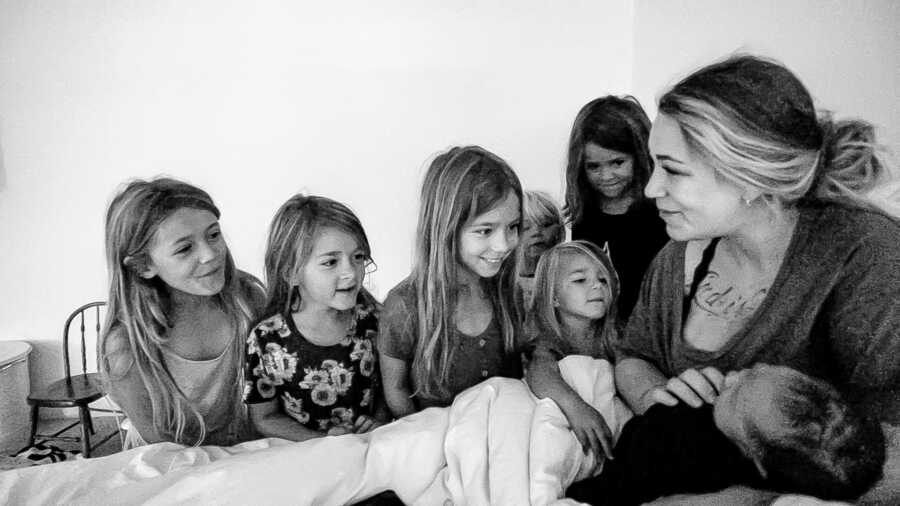 Mom to seven holds her newborn sons while her six daughters look at him with love and admiration