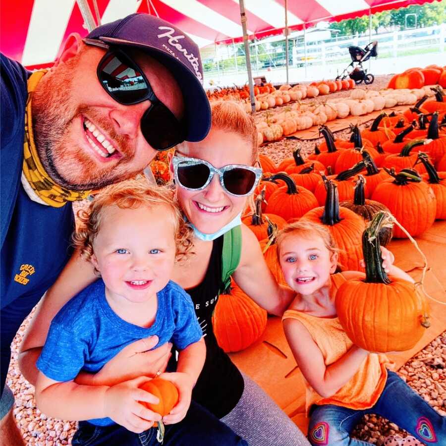 Young man dealing with mental health struggles smiles with his family at a pumpkin patch