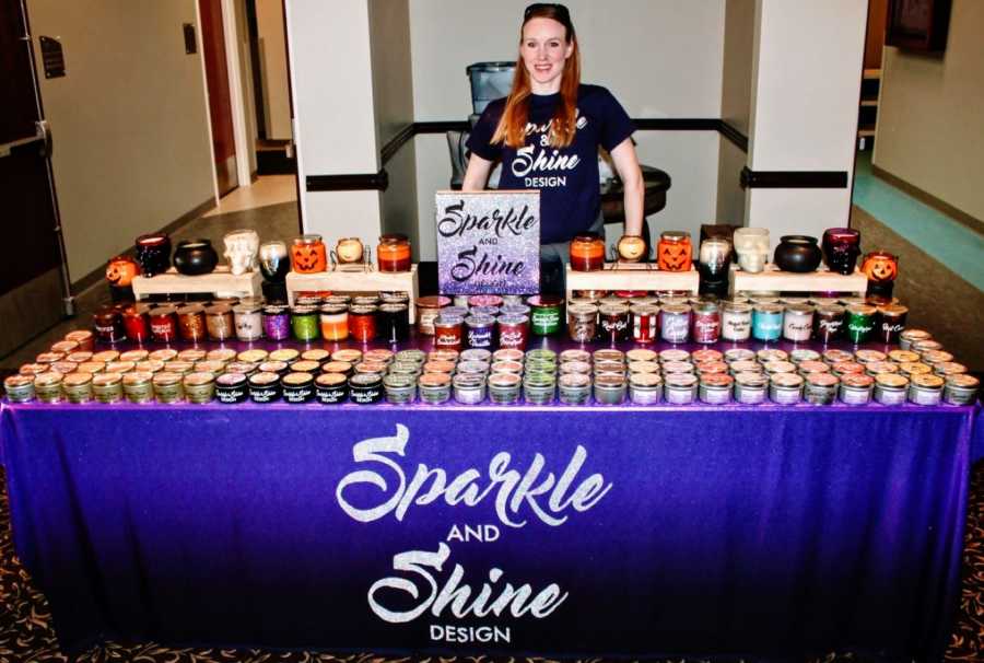 Woman takes photo in front of her homemade candles for her candle business "Sparkle and Shine"