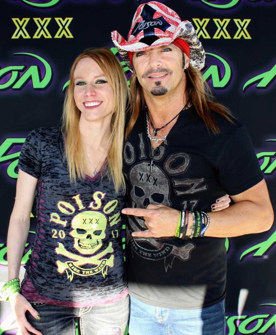 Woman who made hats for Bret Michaels takes a photo with him while they wear matching shirts and he wears her hat