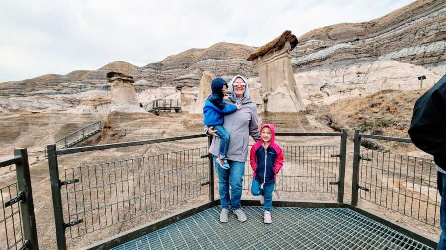 Mom of 2 poses with her son and daughter with a beautiful mountainous scene behind them