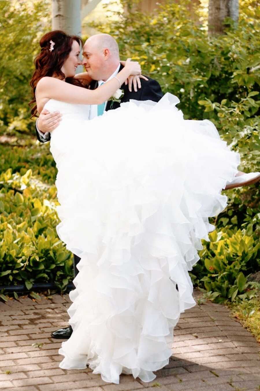 Newlyweds take couples photos together, sharing an intimate moment while the husband holds his wife while they look into each other's eyes