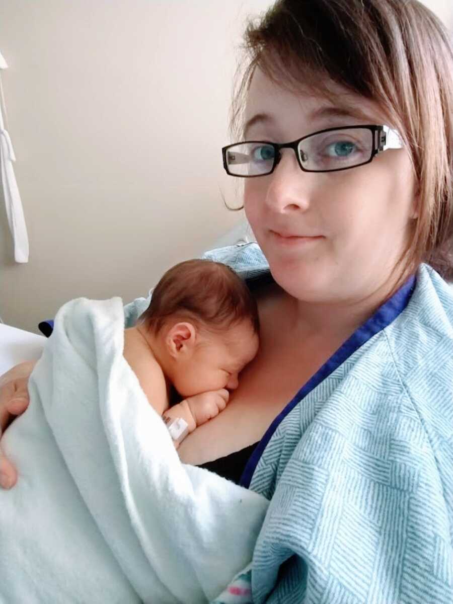 Young woman holds her newborn daughter in the hospital after giving birth to her