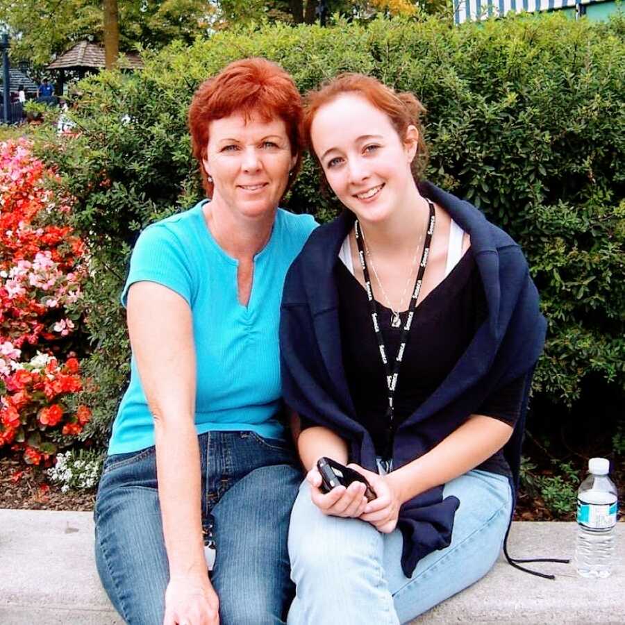 Teen girl takes a photo with her mom while sitting on a concrete bench