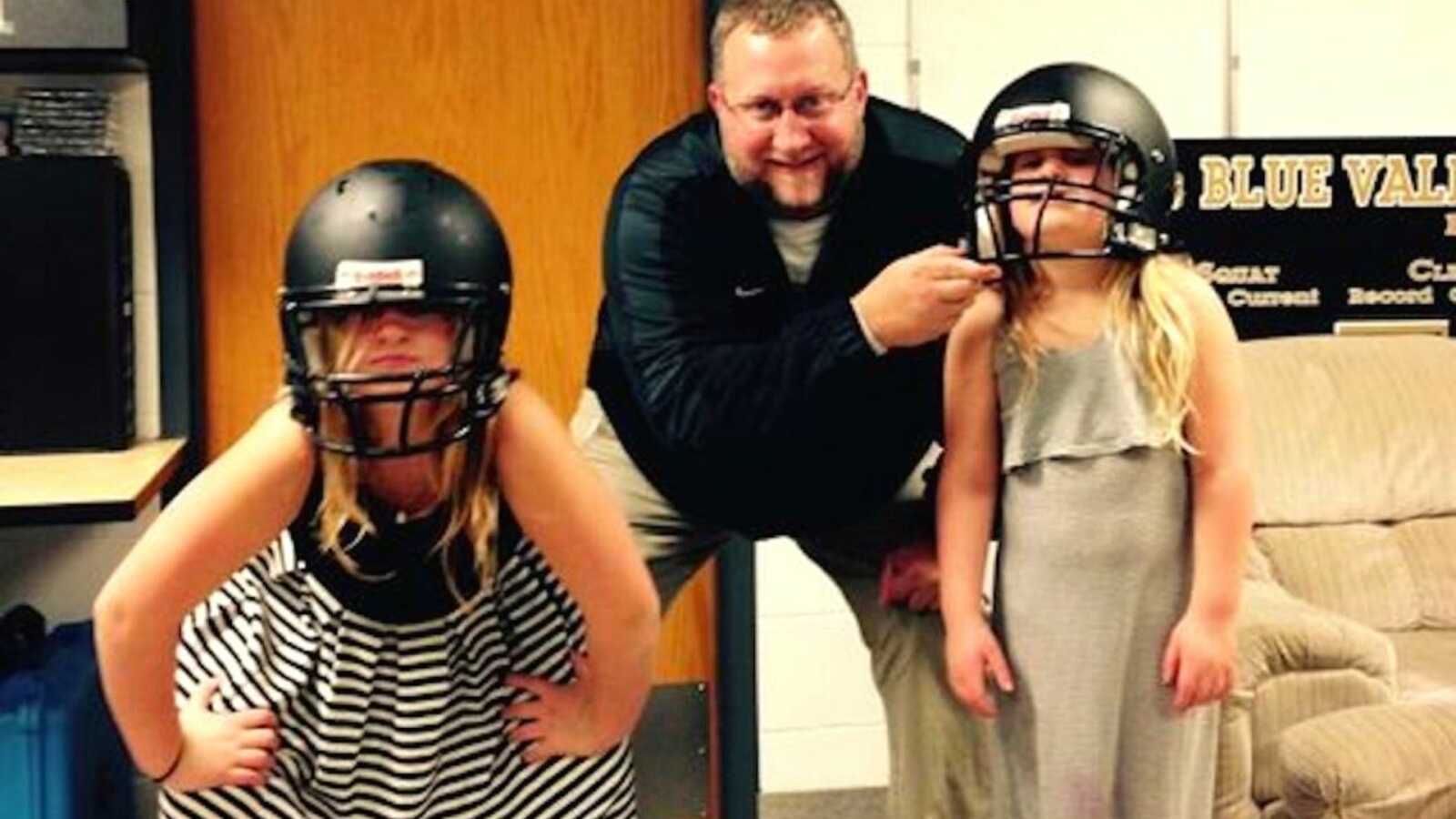 Father with two daughters being silly in football helmets