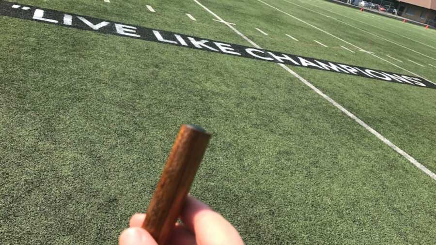 Scattering ashes on field that reads "Live Like Champions"