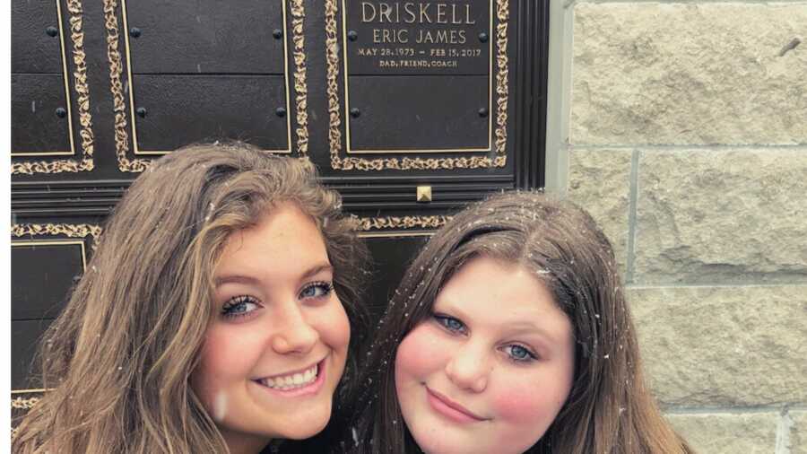 Two daughters smiling in front of father's grave