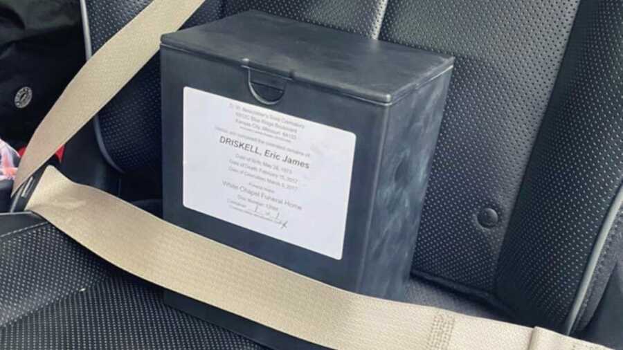 Box of ashes behind seat belt in black car