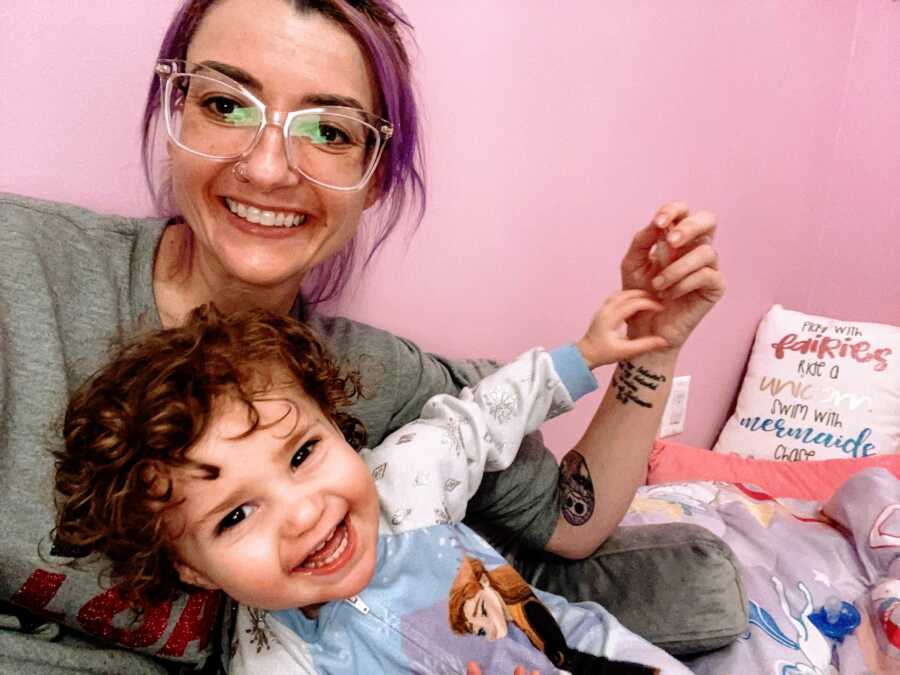 Mom struggling with the grief of losing her husband to Covid-19 takes a selfie with her daughter in her bed while she wears a Frozen onesie